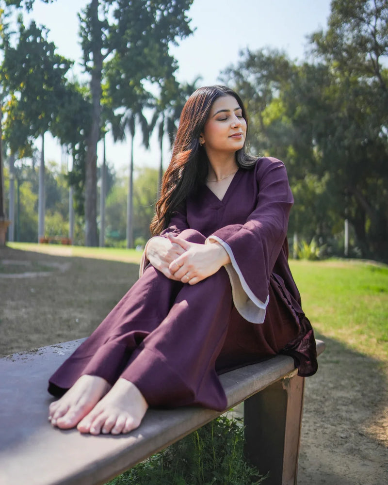 Woman in a purple outfit sitting on a bench in a park