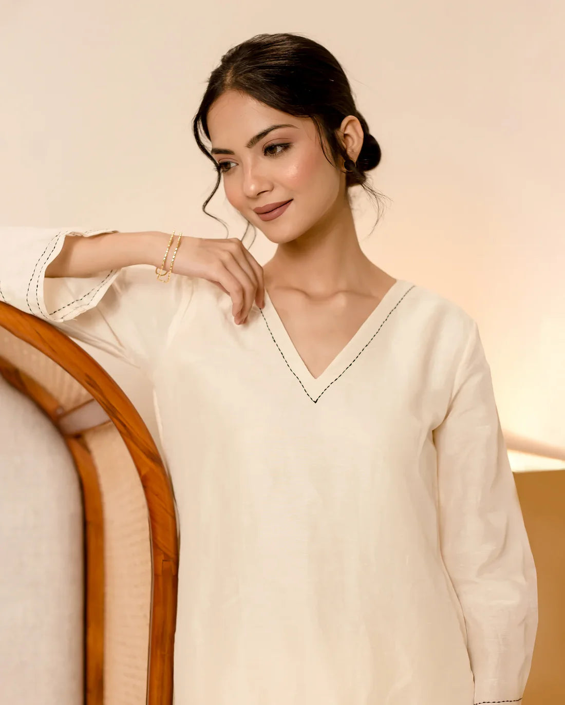 Woman wearing a cream-colored sweater with a neutral background