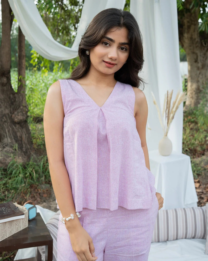 Woman wearing a light purple sleeveless top and pants in an outdoor setting.