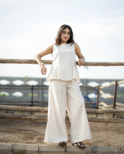 Woman in a white outfit standing on a wooden platform with a blurred background