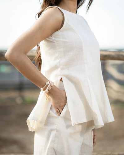 Person wearing a white sleeveless top and pants with a blurred background