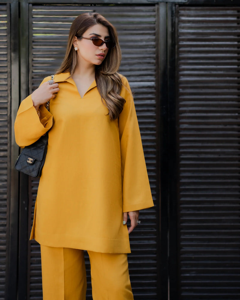 Woman in a yellow outfit standing against a dark background